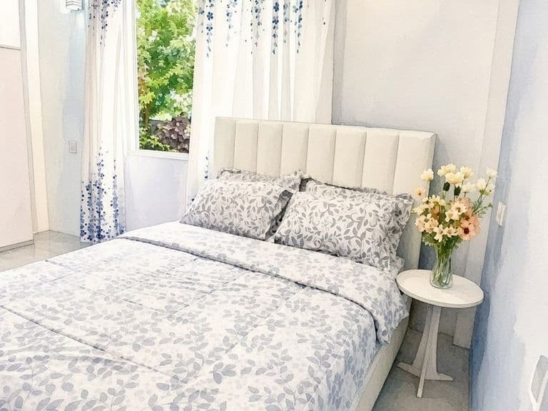 Bedroom with a queen bed, leaf-print linen and fresh flowers on the bedside table